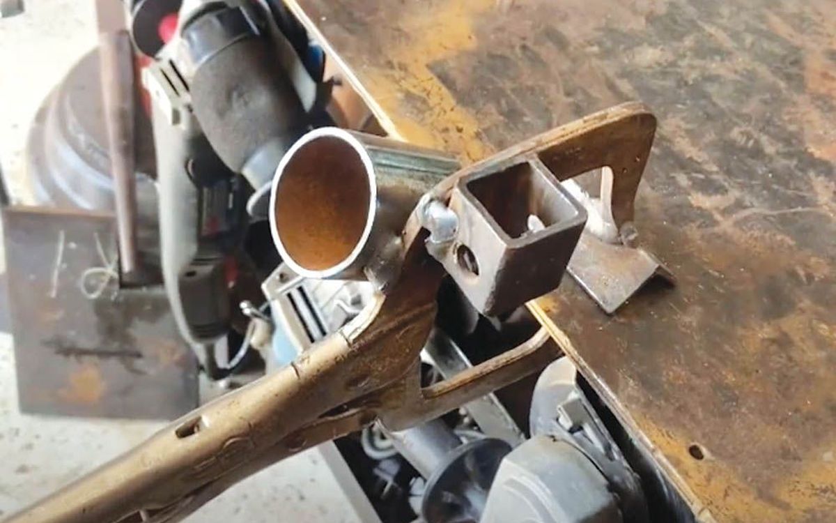 Clamp-on holder made from a locking C-clamp and scrap angle iron holding a MIG gun at a welding table (FARM SHOW photo)