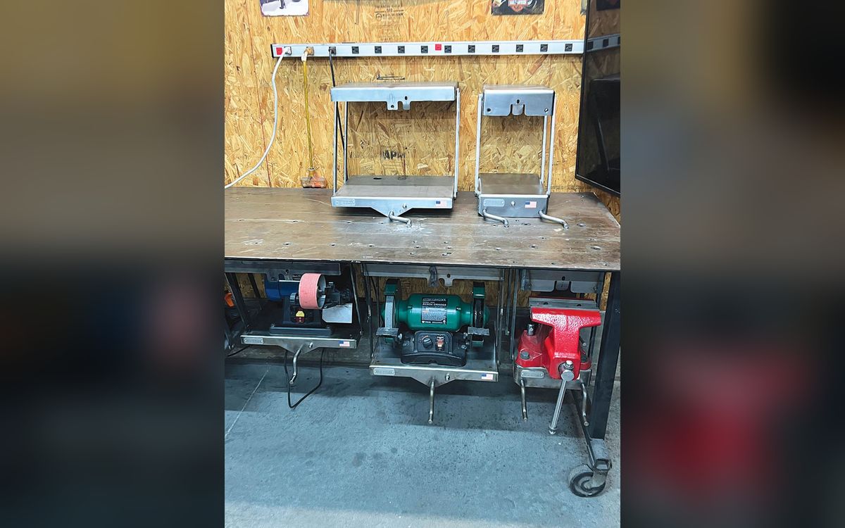Workbench with swing-arm mounts holding bench grinders and a vise (FARM SHOW photo)